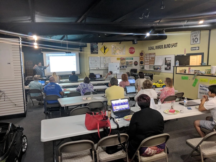 Attendees at a Myrtle Beach WordPress Meetup sitting at tables with laptops while a presenter shows a screen at the front of the room